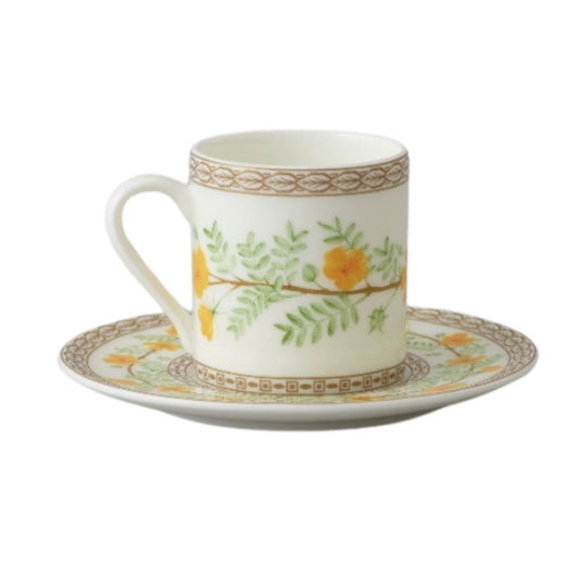 Collation formation curation A white ceramic cup with green and yellow floral patterns, accompanied by a matching saucer.