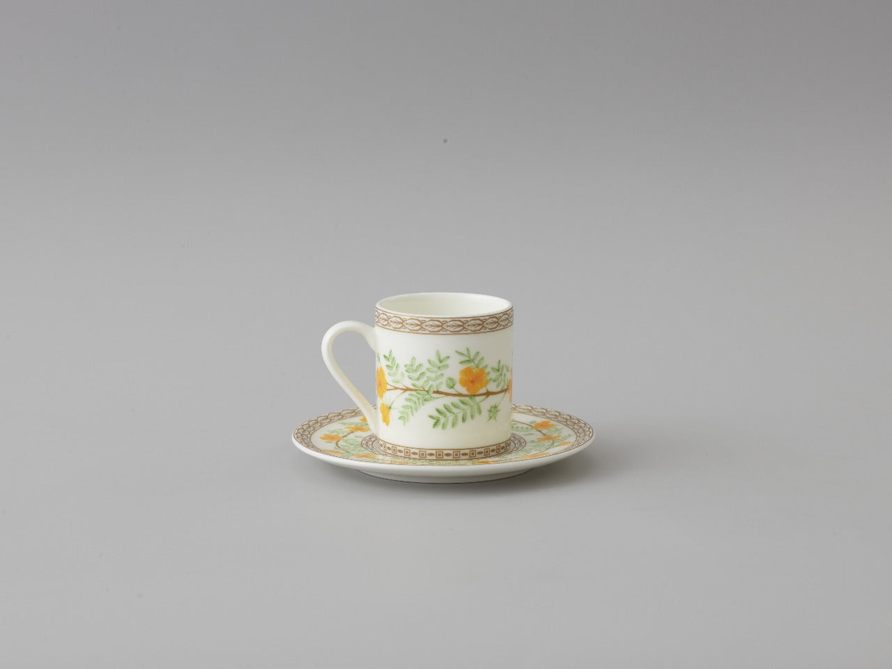 Collation formation curation A white ceramic cup with green and yellow floral patterns, accompanied by a matching saucer.