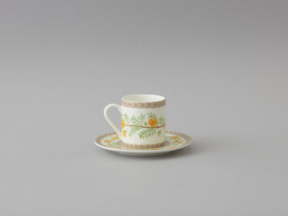 Collation formation curation A white ceramic cup with green and yellow floral patterns, accompanied by a matching saucer.