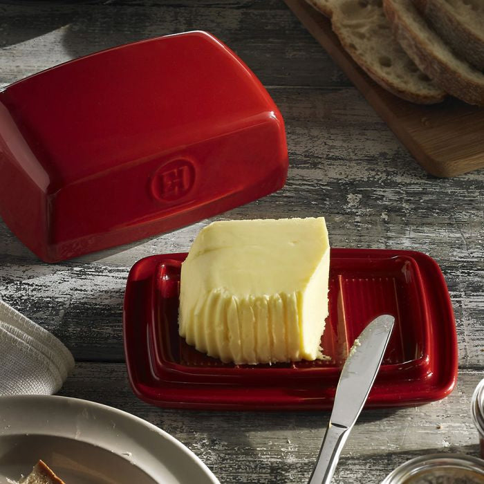 Emile Henry Butter Dish-Red butter dish with a pat of butter and a knife on a wooden surface.