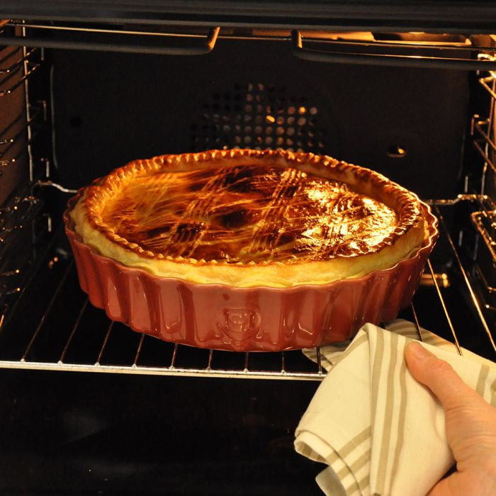 Emile Henry Deep Round Tart Dish, 24cm-Baked dish in an oven with a hand holding a towel