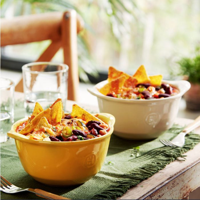 Two bowls of chili with tortilla chips on a table outdoors.