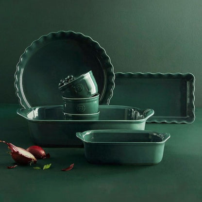 Emile Henry Rectangular Oven Dish-Set of green ceramic cookware including a pie dish, loaf pan, and baking tray on a dark green background.