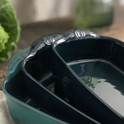 Emile Henry Rectangular Oven Dish-Two green ceramic dishes on a wooden surface with a blurred background