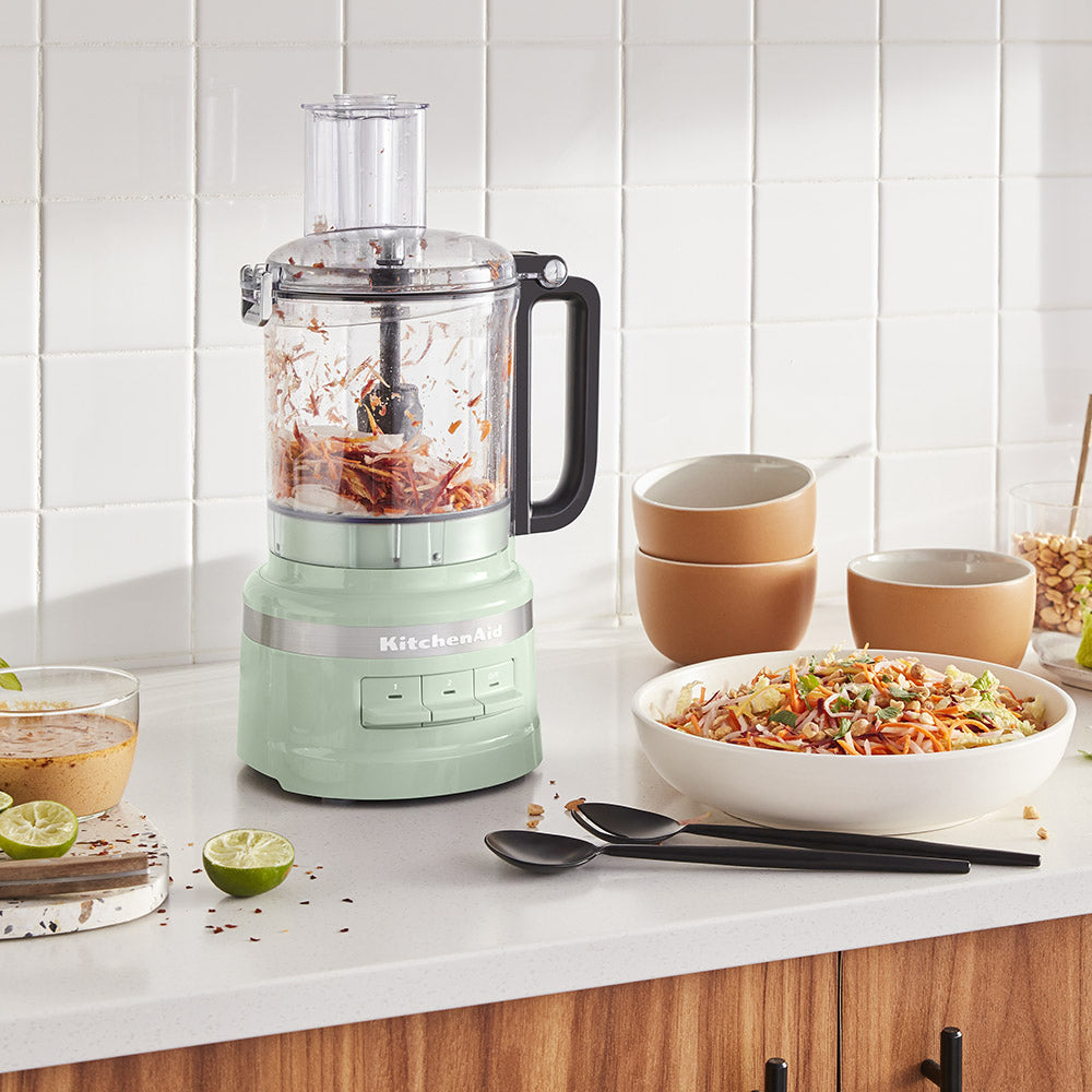 Kitchenaid food processor on a kitchen counter with bowls and ingredients