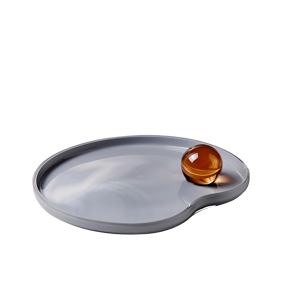 Gray oval tray with a round amber-colored object on a white background