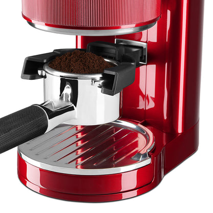 Red espresso machine with a focus on the filter basket and ground coffee.