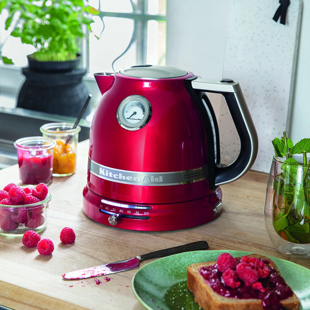 Red KitchenAid kettle on a kitchen counter with berries and toast.