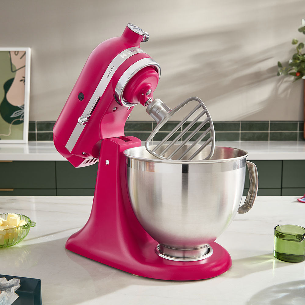 Pink stand mixer with a silver bowl on a kitchen counter