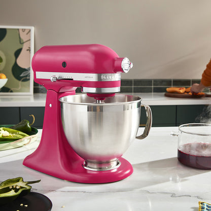 Pink KitchenAid stand mixer with a silver bowl on a kitchen counter.