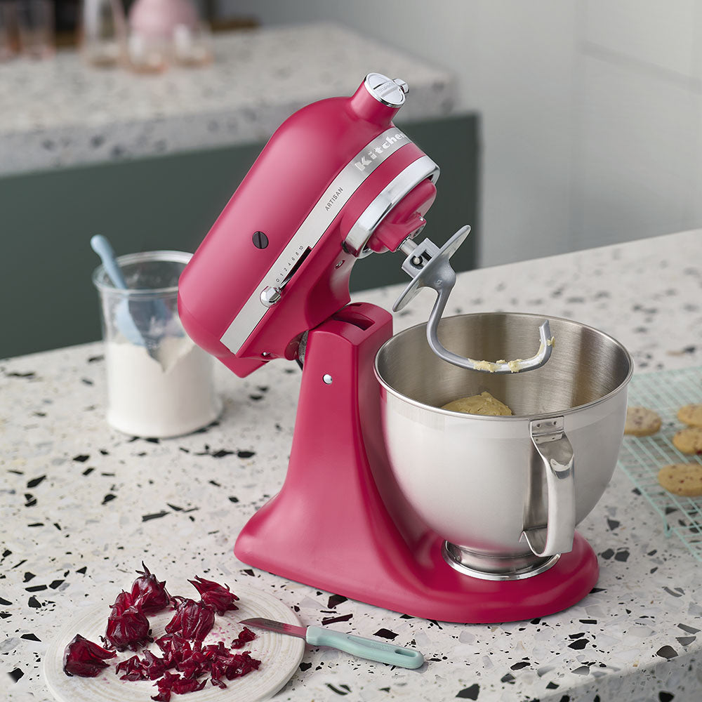 Pink stand mixer with a silver bowl on a kitchen counter.