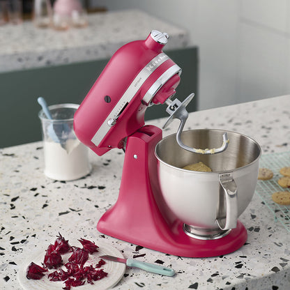 Pink stand mixer with a silver bowl on a kitchen counter.