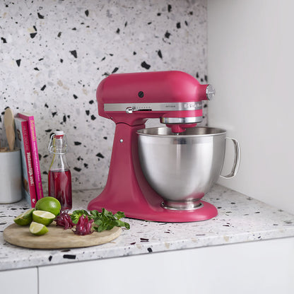 Pink KitchenAid stand mixer on a kitchen counter with limes and a cutting board.
