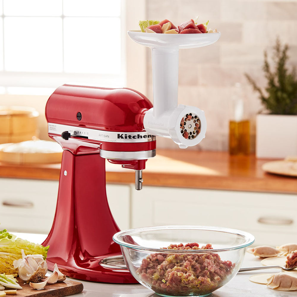 Red KitchenAid stand mixer with a meat KitchenAid Food Grinder- attachment on a kitchen counter.