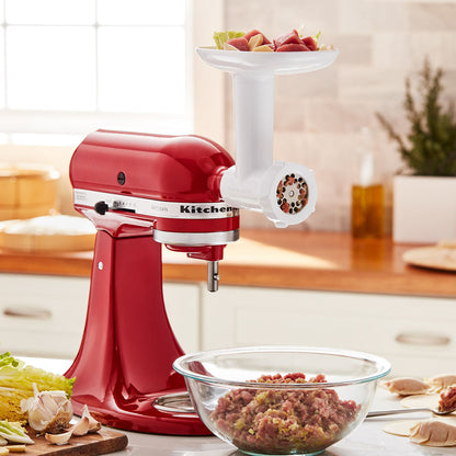 Red KitchenAid stand mixer with a meat KitchenAid Food Grinder- attachment on a kitchen counter.