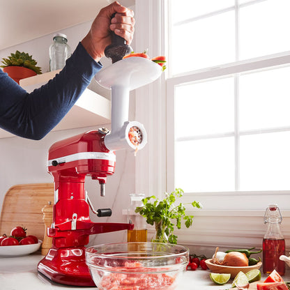 KitchenAid Food Grinder-Red stand mixer on a kitchen counter with a person using it