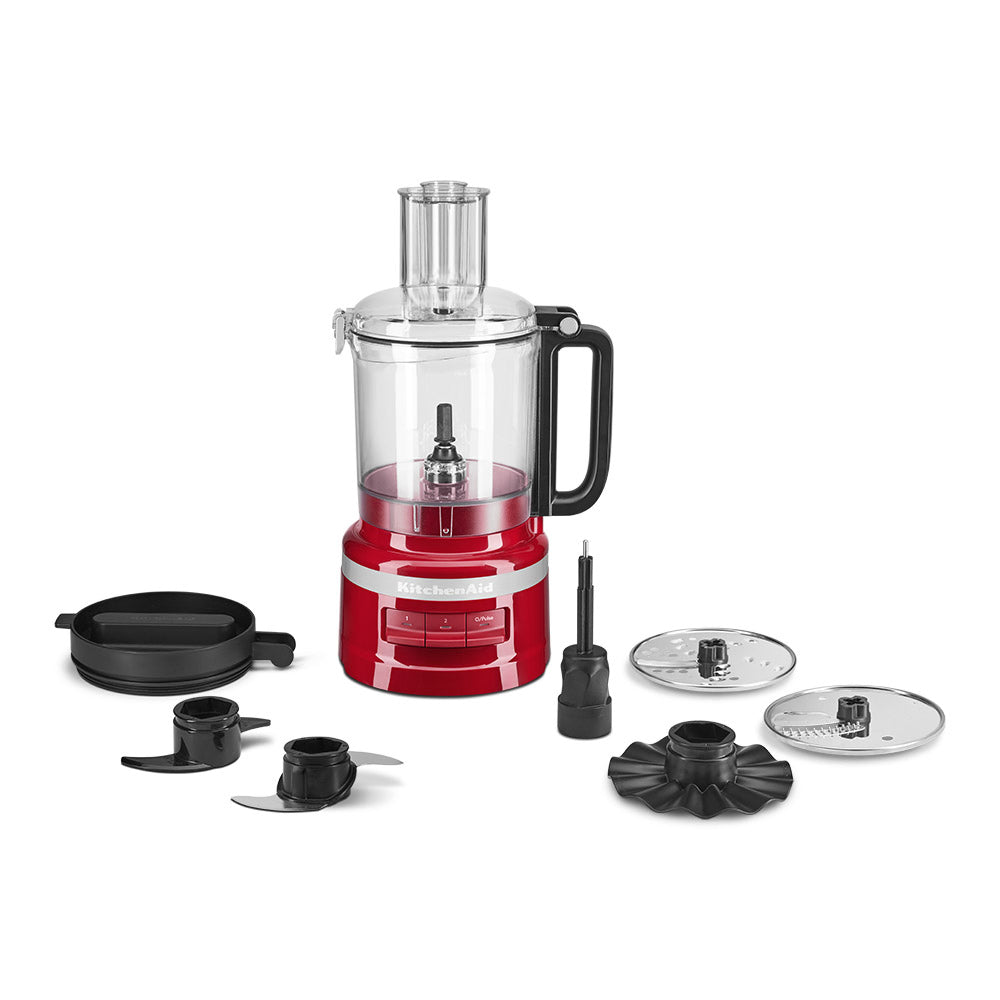 Red food processor with attachments on a white background
