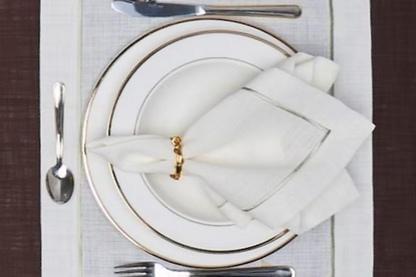 Lusso Dinner Napkin Set of 4-Elegant table setting with white plates, silverware, and folded napkin on a textured surface.