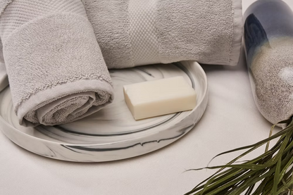 Roma Towel Set-Gray towel on a marble tray with a bar of soap and a plant on a light background