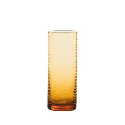 Amber glass tumbler with textured surface on a white background