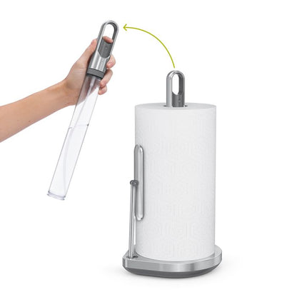 Simplehuman Kitchen Roll Holder with Spray Pump Hand holding a clear plastic bottle over a paper towel holder with a roll of paper towels.