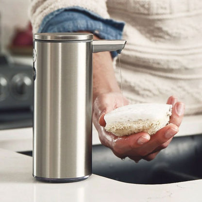 Simplehuman Liquid Dish Soap Person holding a bar of soap next to a stainless steel soap dispenser on a kitchen counter.