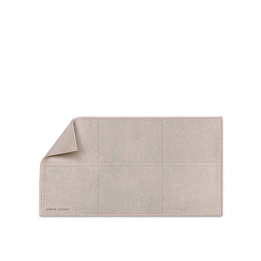 Beige bath mat with a textured pattern on a white background