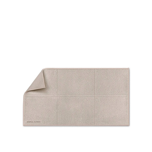 Beige bath mat with a textured pattern on a white background