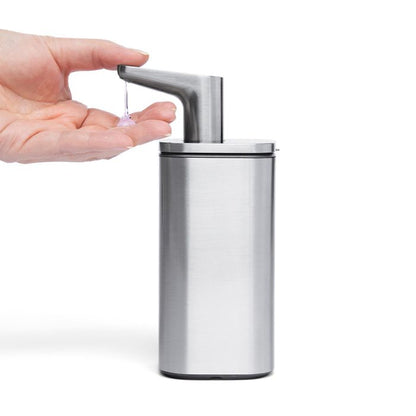 Simplehuman Pulse Pump Hand pressing a silver soap dispenser 
