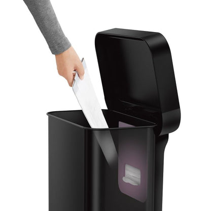 Simplehuman Rectangular Pedal Bin with Liner Pocket Black trash bin with a hand disposing of white paper 