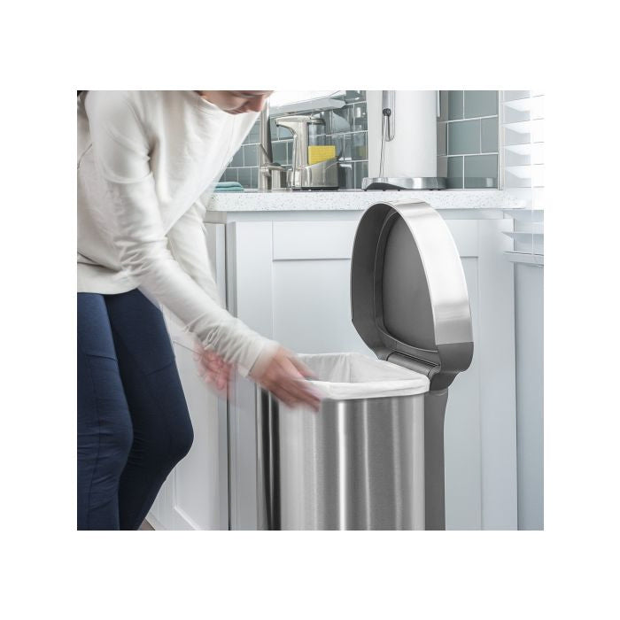 Simplehuman Semi Round Sensor Bin With Liner Pocket-Person interacting with a modern kitchen trash can in a bright kitchen setting