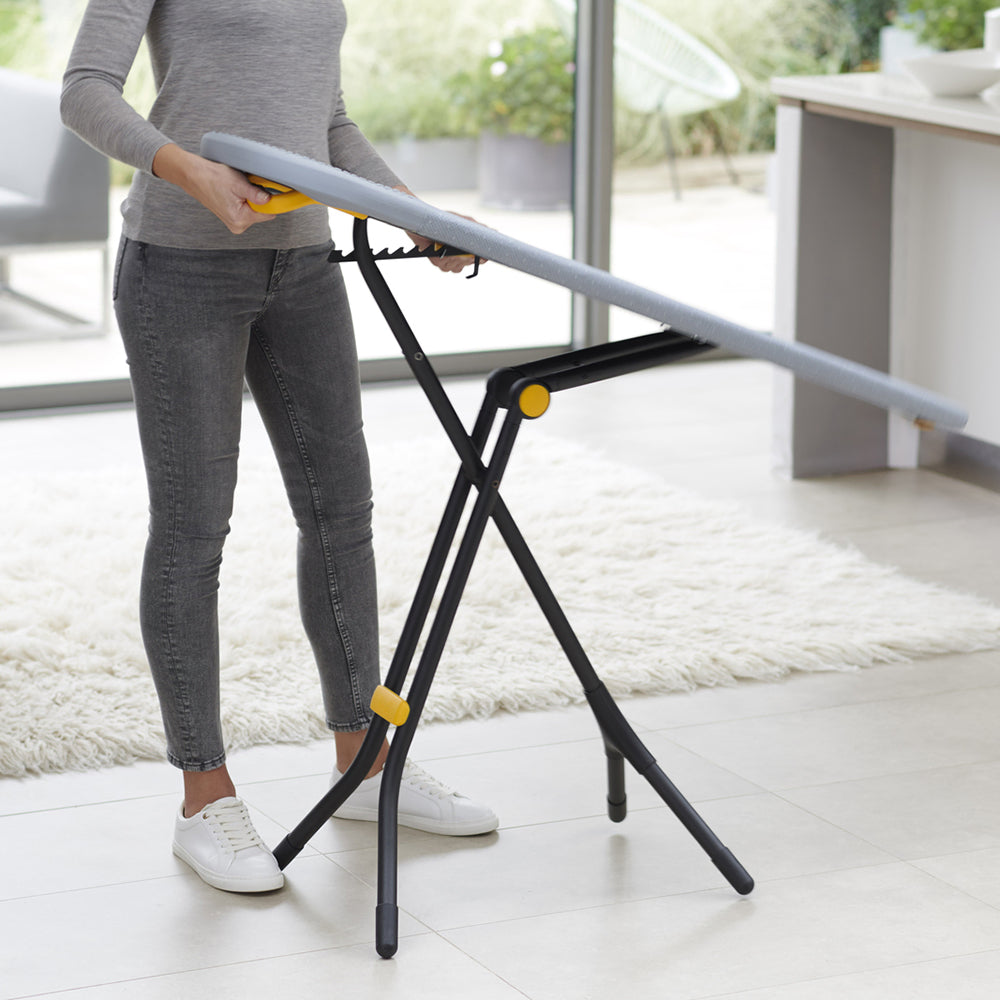 UAE laundry room-Person using a portable ironing board stand indoors.