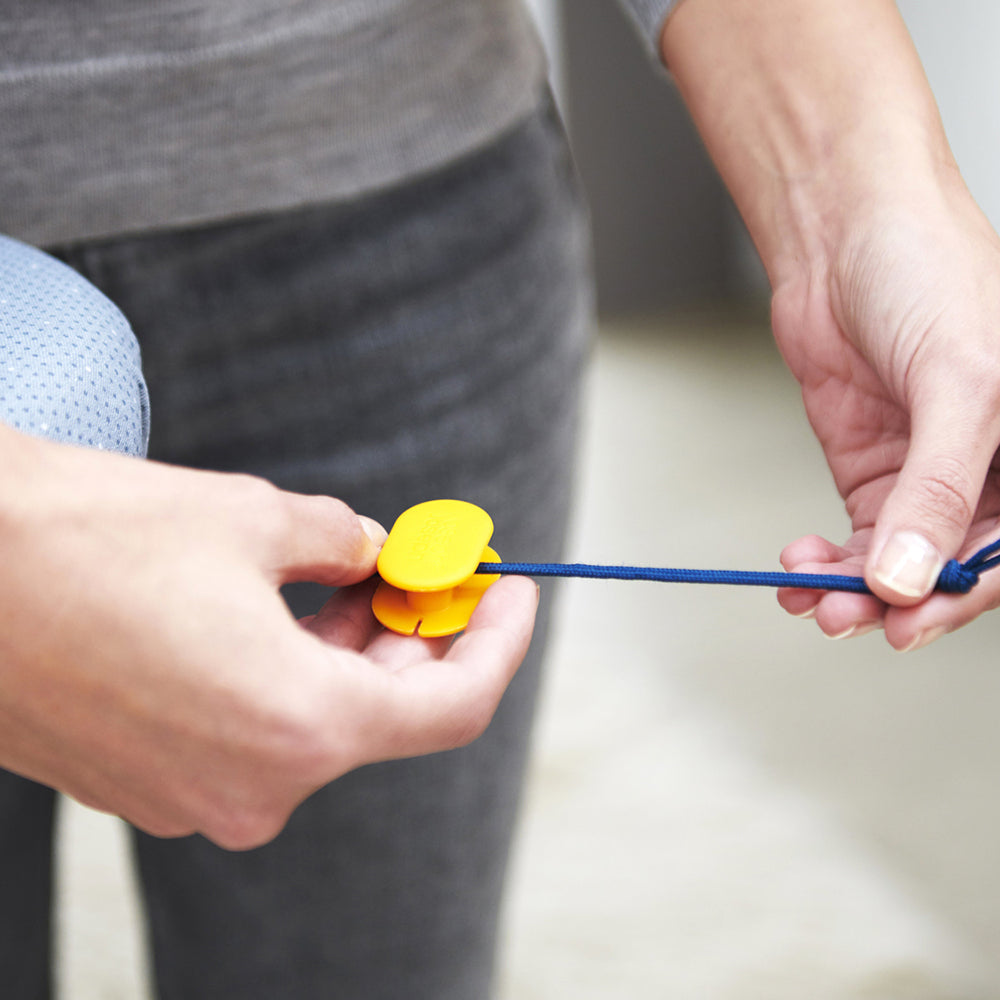 UAE laundry room-Person holding a yellow flower and blue string, blurred background
