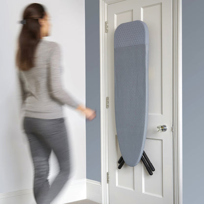 UAE laundry room-Person walking past a door with a blue ironing board attached to it.
