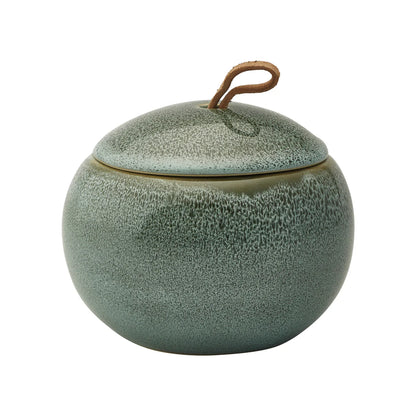 Green ceramic jar with textured surface and wooden handle on a white background