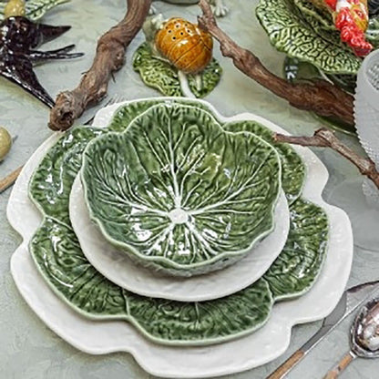 Set of green ceramic plates with leaf design on a light gray surface.
