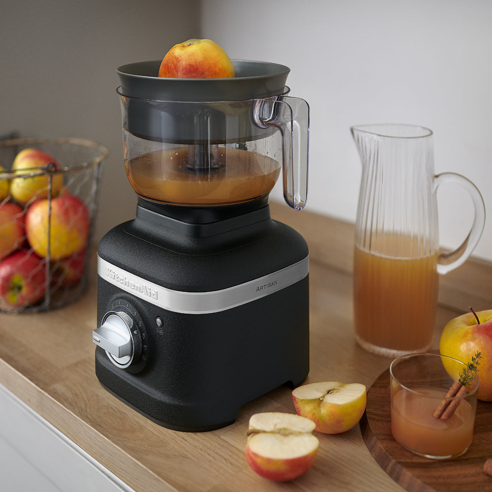 KitchenAid Black KitchenAid juicer with apples and juice on a wooden countertop