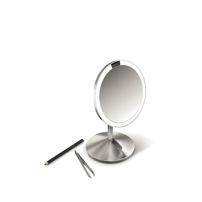 Simplehuman Sensor Mirror Fold with Travel Case-Silver makeup mirror with a pencil and tweezers on a white background