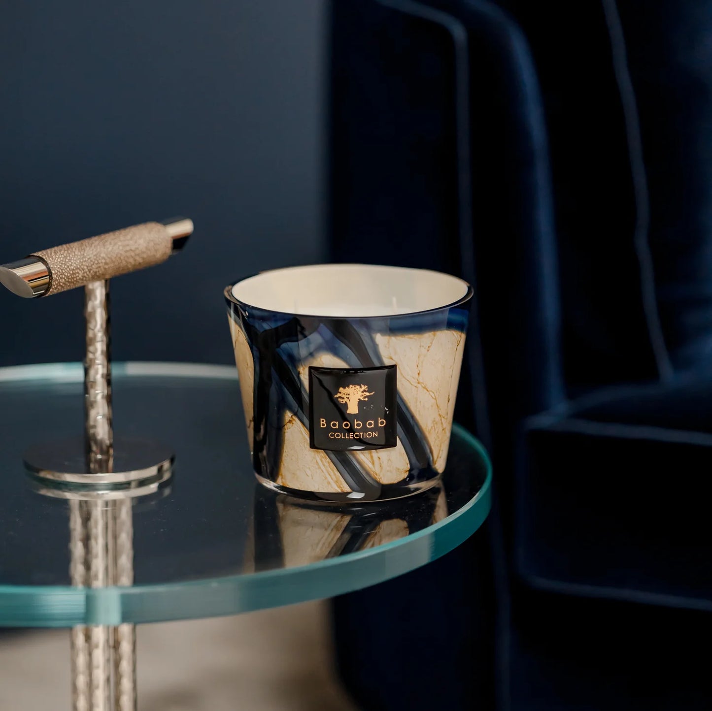 scented candles-Candle with a brand logo on a glass table against a dark background