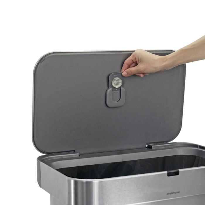 Hand opening a gray lid of a trash bin with a visible brand logo.