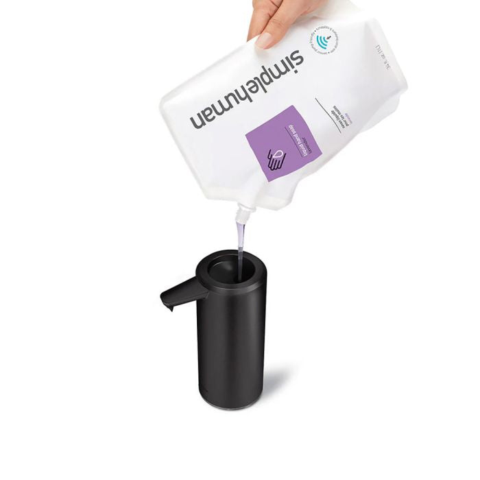 simplehuman Rechargeable Sensor Soap Pump-Hand pouring a white container labeled 'simphuman' into a black dispenser on a white background