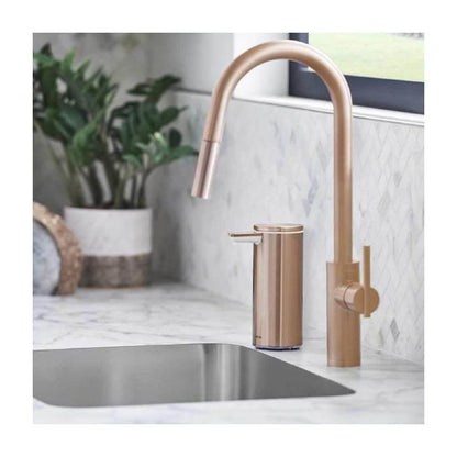 simplehuman Rechargeable Sensor Soap Pump-Rose gold kitchen faucet and soap dispenser on a marble countertop with a plant in the background.