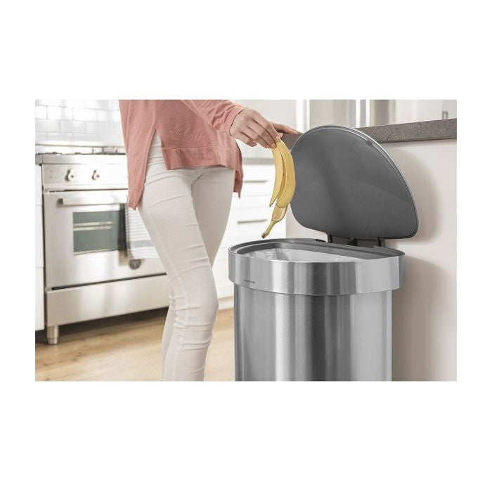 simplehuman Semi Round Step Bin, 45L-Person disposing of a banana peel into a kitchen trash can.