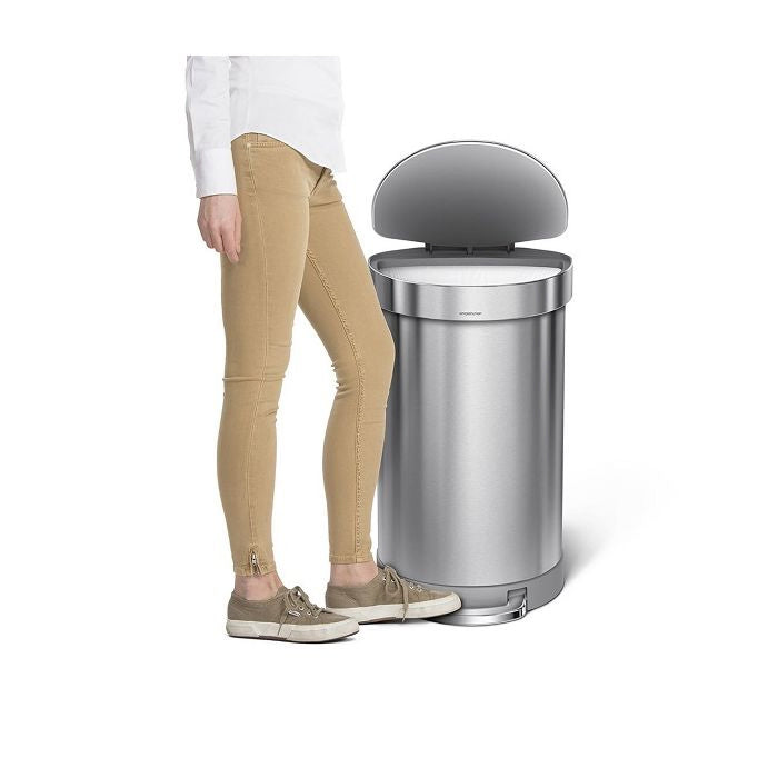simplehuman Semi Round Step Bin, 45L-Person standing next to a large silver trash can on a white background